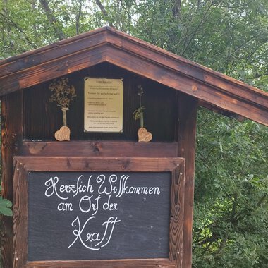 Ein traditionelles Holzschild mit der Aufschrift "Herzlich Willkommen an den Ötztal". Umgeben von grünen Bäumen und einer ländlichen Umgebung. | © Nicole Lughammer