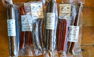 Auf dem Bild sind verschiedene Wurstsorten in durchsichtigen Verpackungen zu sehen. Die Würste sind farblich unterschiedlich und tragen Etiketten mit Produktinformationen. | © Kleinwalsertal Tourismus | Oliver Farys