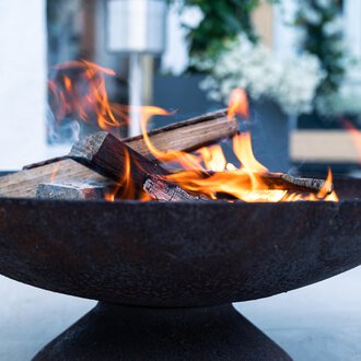 A rustic fire in a round fire pit. The flames flicker over the logs and create a cozy atmosphere. | © Genuss- & Aktivhotel Sonnenburg