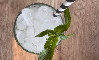 A refreshing drink with ice cubes and fresh mint. A striped straw completes the picture. | © MORE VIBES by Alex Lambsdorff