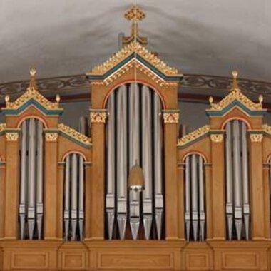 Eine prachtvolle Orgel mit kunstvollen Verzierungen in warmen Holzfarben. Die Pfeifen sind symmetrisch angeordnet und erheben sich über dem Bühnenbereich. | © Karl Kessler