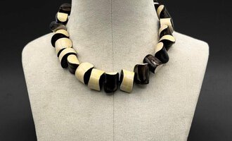 An elegant necklace made of alternating black and white pearls. It has a curved shape and adds a stylish look. | © Gerti Maitz
