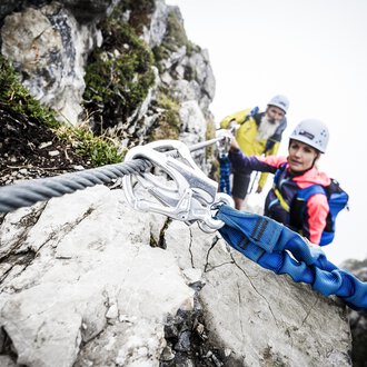 Zwei Kletterer sichern sich an einem steilen Felsen. Es ist neblig und die Umgebung wirkt herausfordernd und abenteuerlich. | © Bergschule Kleinwalsertal | Dominik Berchtold