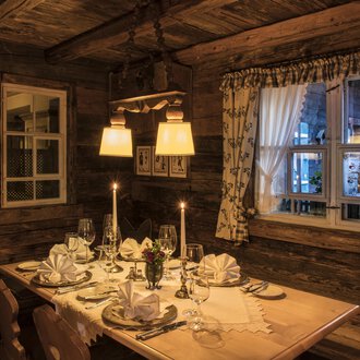 Ein gemütliches Restaurant mit einem schön gedeckten Tisch. Die warmen Lichter und Holzwände schaffen eine einladende Atmosphäre. | © Alpahotel Walserstuba GmbH Patrik Säly Photography