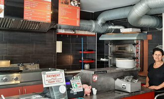 Ein einladendes Restaurant mit einer offenen Küche und einem freundlichen Ambiente. Im Hintergrund sind die Speisekarten und verschiedene Küchengeräte zu sehen. | © Alpengrill Riezlern | Veronika Senn