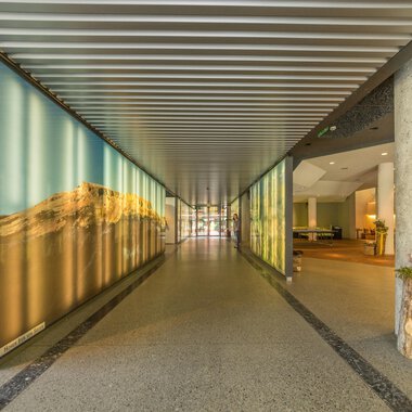 A modern entrance area with bright walls and a long hallway. On both sides, creative wall designs can be seen. | © Kleinwalsertal Tourismus |  Steffen Berschin