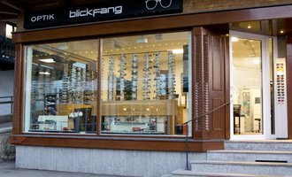 An optical shop with large windows and a selection of sunglasses. The store has a sign that says "blickfang" and has a modern design. | © Blickfang | Michael Stumpe