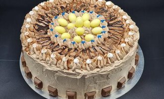 Eine dekorative Schokoladentorte mit buntem Topping und einer Kreation aus Creme. Sie ist mit kleinen Schokoladenstückchen und bunten Eiern verziert.