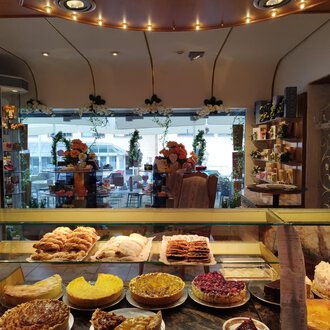 A cozy bakery with a selection of sweet and savory baked goods. In the background, you can see tables and chairs for guests. | © Kleinwalsertal Tourismus | N. Lughammer