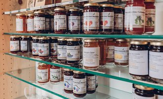 A collection of jam jars on a shelf. The jars are in different colors and labeled with tags. | © Carolin Ries | www.calejofotografie.de