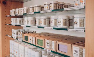 A shelf with various containers and boxes for natural products. The products are neatly arranged and labeled. | © Carolin Ries | www.calejofotografie.de