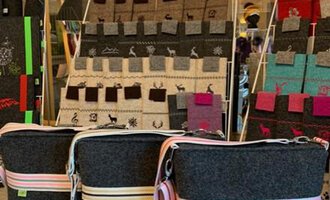 Drei stilvolle Taschen aus Filz mit farbigen Streifen stehen im Vordergrund. Im Hintergrund sind weitere Taschen in verschiedenen Farben und Designs zu sehen. | © Chrömle Schönes aus Filz | Anke Drechsel