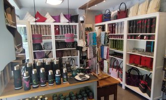 Ein stilvoller Laden mit Regalen, die verschiedene Taschen und Accessoires ausstellen. Auf einem Tisch im Vordergrund sind diverse Trinkflaschen und Produkte angeordnet. | © Chrömle Schönes aus Filz | N. Lughammer