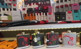 Eine Auswahl an stilvollen Flaschen in verschiedenen Designs steht auf einem Regal. Im Hintergrund sind viele bunte Accessoires und Taschen zu sehen. | © Chrömle Schönes aus Filz | N. Lughammer