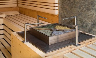 Ein moderner Saunabereich mit einem quadratischen Behälter, der verschiedene Kräuter enthält. Die Wände und Bänke sind aus hellem Holz gefertigt. | © Hotel Leitner