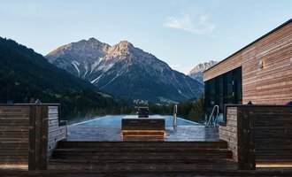 An infinity pool with a view of majestic mountains. The wooden veranda creates a cozy atmosphere in nature. | © A-ROSA Ifen Hotel Kleinwalsertal