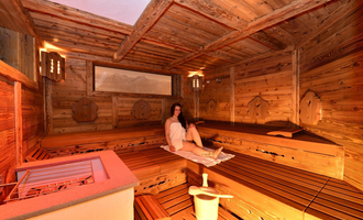Eine gemütliche Sauna mit Holzwänden und Bänken. Eine entspannte Person sitzt im Raum und genießt die Wärme. | © Hotel Alpenstüble KG