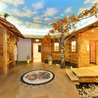 A cozy wellness area with wooden paneling and beautiful tree decorations. The ceiling features a clear sky, creating a relaxing atmosphere. | © Hotel Alpenstüble KG | Manuel Riezler