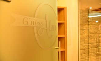 A door with the inscription "G'nuss Alm" is visible in the image. The area seems to be inviting and modernly designed. | © Hotel Alpenstüble KG | Manuel Riezler
