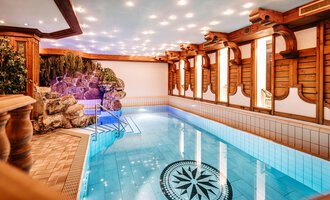 A beautiful indoor pool with clear, blue water and decorative wooden elements. The atmosphere is calm and inviting, perfect for relaxing. | © Hotel Alpenstüble KG