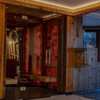 Ein moderner Empfangsbereich mit Holzelementen und großen Glasflächen. Die gemütliche Atmosphäre wird durch warmes Licht und geschmackvolle Dekorationen verstärkt. | © IFA Hotel Alpenhof Wildental | Andreas Froschauer