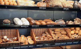 Ein Regal voller frischer Brötchen und Brote in verschiedenen Formen. Die Auswahl reicht von Körnerbrötchen bis zu klassischen Broten. | © Ehrat´s Backmanufaktur | Veronika Senn