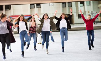 Eine Gruppe von fröhlichen Jugendlichen läuft auf einer Eisbahn. Sie lachen und haben Spaß beim Eislaufen. | © Sportstätten Oberstdorf | Veronika Lindlbauer