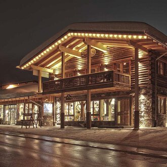 A charming wooden building with warm light at night. The facade is cozy and inviting. | © Fun-Alp
