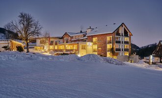A cozy hotel in a snowy landscape. The evening sky is clear and the buildings are beautifully illuminated.