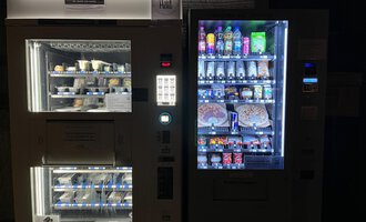 Zwei Verkaufsautomaten stehen nebeneinander. Der linke Automat bietet gefrorene Lebensmittel, während der rechte verschiedene Getränke und Snacks enthält. | © Gerd am Herd | Gerd Hammerer