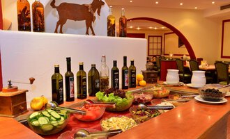 Ein schön dekorierter Buffetbereich mit frischen Lebensmitteln und verschiedenen Flaschen Öl. Im Hintergrund ist eine Wanddekoration mit einer Ziege zu sehen. | © IFA Breitach Apartements