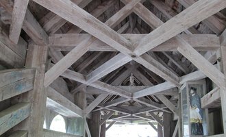 Eine alte Brücke mit einem hölzernen Dach und sichtbaren Streben. Der Innenraum ist hell und führt zu einem offenen Ende. | © Stefan Heim