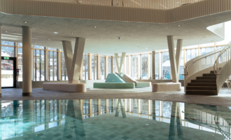 Ein modernes Schwimmbad mit glasklarem Wasser und eleganten Design. Personen entspannen sich im Wasser und genießen die Atmosphäre. | © Tourismus Oberstdorf