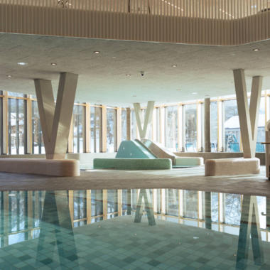 Ein modernes Schwimmbad mit glasklarem Wasser und eleganten Design. Personen entspannen sich im Wasser und genießen die Atmosphäre. | © Tourismus Oberstdorf