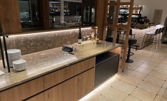 Eine moderne Bar mit Holz- und Steindetails. Der Raum ist hell und einladend, mit einem großzügigen Sitzbereich im Hintergrund. | © Almhof Rupp | Lukas Kind