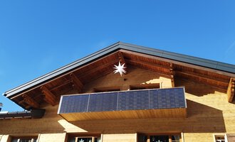 A modern wooden house with a balcony and photovoltaic panels. The clear blue sky creates a friendly atmosphere. | © Kleinwalsertal Tourismus | N. Lughammer