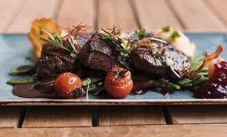 A delicious dish with juicy meat, refined with herbs and fresh tomatoes. It is accompanied by an impressive presentation on an elegant plate.