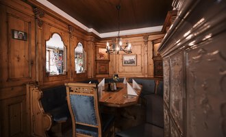 A cozy interior with wooden walls and a large table. The decor is traditional and inviting.