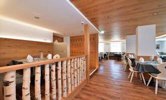 A modern designed restaurant with wooden walls and an inviting atmosphere.  
Tables are set with covered plates, and the floor is made of wood. | © Hotel Tradizio GmbH | Werbewind GmbH