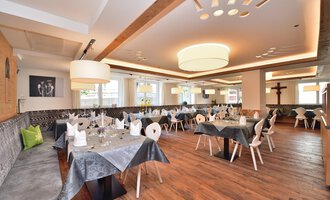An elegant restaurant with wooden floors and modern tables. The tables are beautifully set and the lighting is soft. | © Hotel Tradizio GmbH | Werbewind GmbH