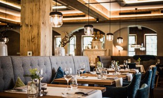 Ein stilvolles Restaurant mit eleganten Tischen und bequemen Sitzplätzen. Die gemütliche Atmosphäre wird durch sanfte Beleuchtung und natürliche Materialien hervorgehoben. | © Verwöhn- & Wellnesshotel Walserhof| Aileen Melucci