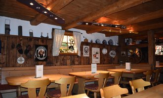 Ein gemütliches Restaurant mit Holzmöbeln und rustikalem Ambiente. Die Wände sind geschmückt mit dekorativen Tellern und Bildern. | © s‘Älpele | Marco Mitterer