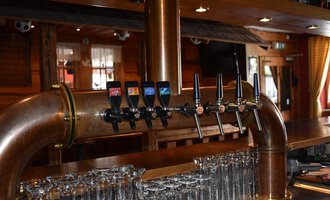 A well-structured bar with several beer taps and glasses. The wooden paneling creates a cozy atmosphere. | © s‘Älpele | Marco Mitterer