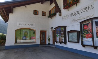 Ein charmantes Gebäude mit blühenden Fensterkästen. Es beherbergt einen Salon und eine Drogerie. | © Kleinwalsertal Tourismus