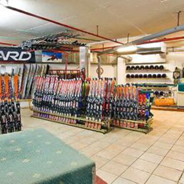 A ski rental shop with many skis and snowboards in a well-organized space. The walls are covered with equipment and accessories for winter sports. | © Aparthotel Kleinwalsertal Haller GmbH & Co KG
