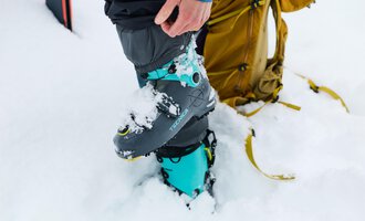 A man is repairing ski equipment and assembling a ski boot. In the background, numerous skis are standing. | © Kleinwalsertal Tourismus | Oliver Farys