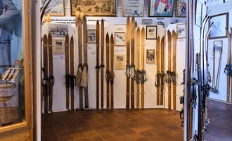 An exhibition with old skis and equipment. The walls are decorated with historical information and images. | © Kleinwalsertal Tourismus | Oliver Farys