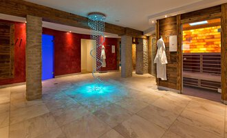 Ein moderner Wellnessbereich mit sanften Beleuchtungseffekten. An den Wänden befinden sich Holzelemente und Saunatüren. | © Aparthotel Kleinwalsertal Haller GmbH & Co KG