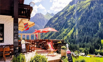 Ein gemütliches Restaurant mit Sitzplätzen im Freien und Blick auf die Berge. Die Umgebung ist grün und malerisch, ideal für eine entspannende Auszeit. | © Starzelhaus Pizzeria La Marmotta | J. Reich-Ulicny