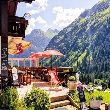 Ein gemütliches Restaurant mit Sitzplätzen im Freien und Blick auf die Berge. Die Umgebung ist grün und malerisch, ideal für eine entspannende Auszeit. | © Starzelhaus Pizzeria La Marmotta | J. Reich-Ulicny